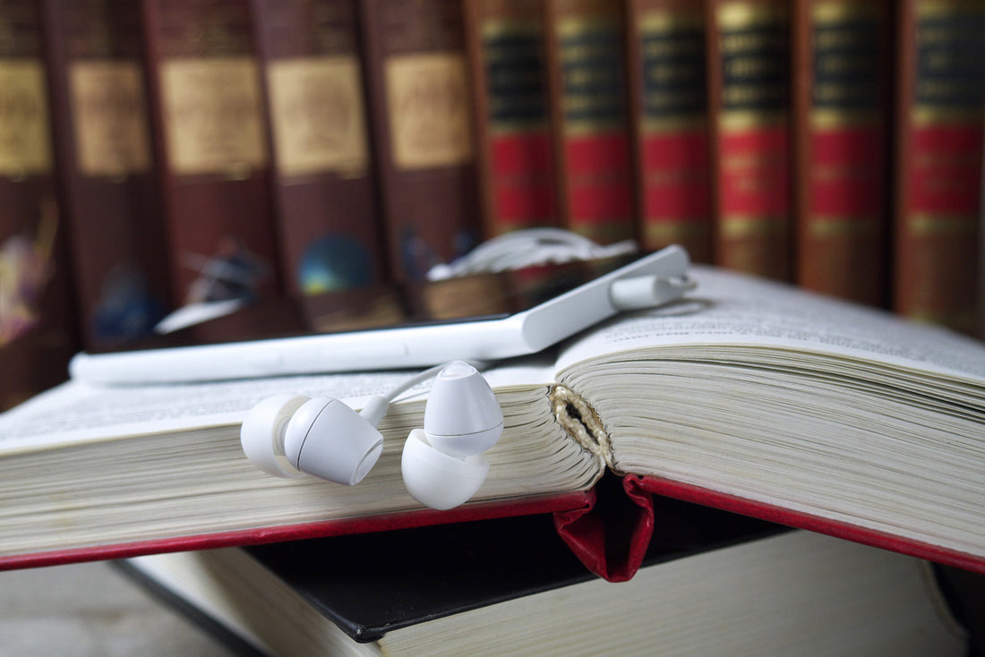 Audiobook device with headphones on open paper book