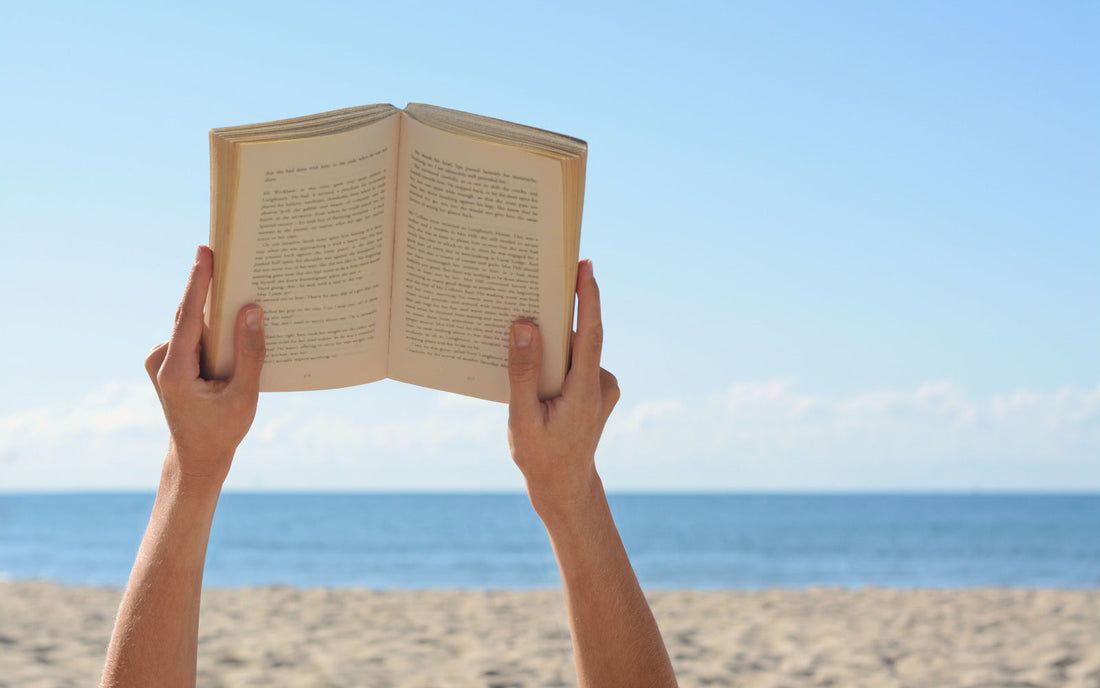 Person holding book up at the beach