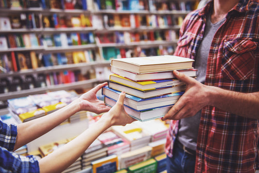Person buying a stack of books in a book store