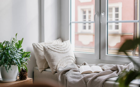 Window seat in home with blanket and pillows to create a cozy reading space