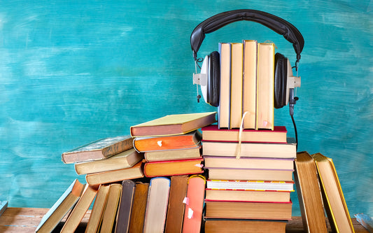 stack of books with headphones for listening to audiobooks