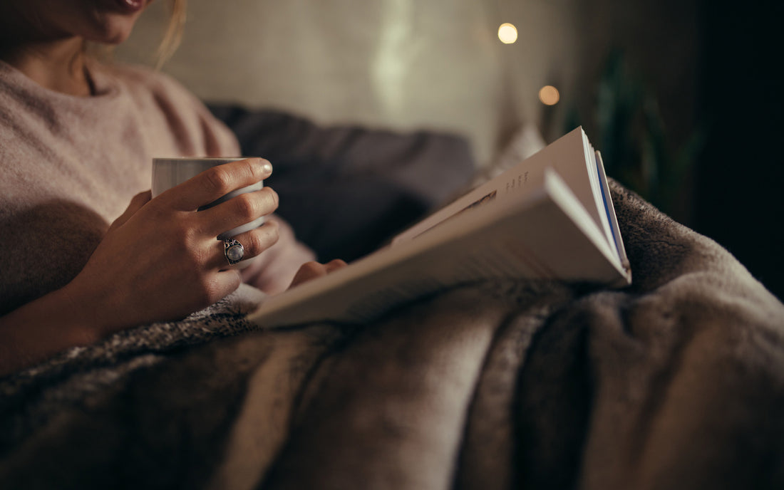 Woman reading a cozy book on a chair with a warm coffee