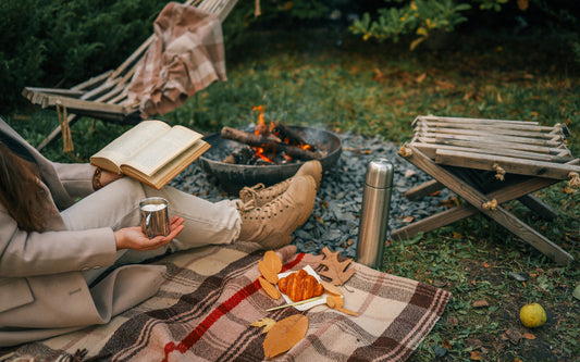 Person reads a book while camping in the fall