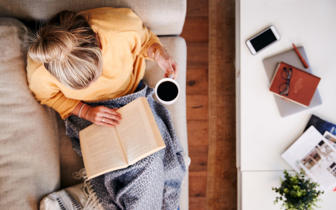 Woman reads new release book on couch