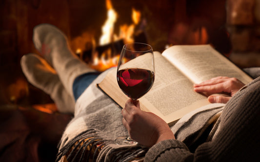 Woman reads romance novel with a glass of wine